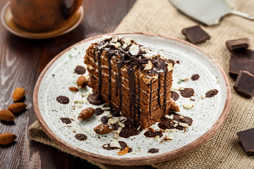 Slice of delicious chocolate Spartak cake on a rustic plate. First class dessert on a white wooden table.