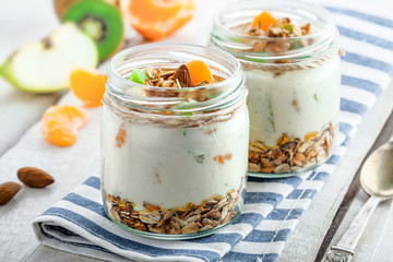Healthy homemade granola with yogurt and fruits in a rustic jar. Traditional American food on a table. Classic snack.