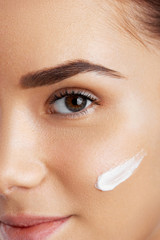Beautiful woman face. Skincare habits. Face of young woman. Girl taking care of her dry complexion applying moisturizing cream. Beauty treatment.