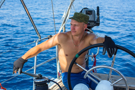 Young man skipper of a sailing yacht. Luxury vacation. Extreme sports.