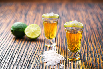 Two shot of gold tequila on a  brown wooden background ,selectiv