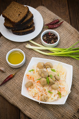 Braised cabbage with carrots and mushrooms in a bowl. Wooden background. Top view. Close-up