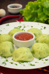 Georgian dumplings Khinkali of spinach dough with meat and tomato spicy sauce satsebeli. Wooden background. Top view. Close-up
