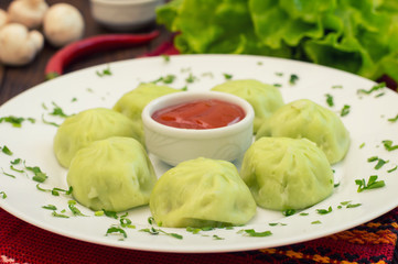 Georgian dumplings Khinkali of spinach dough with meat and tomato spicy sauce satsebeli. Wooden background. Top view. Close-up