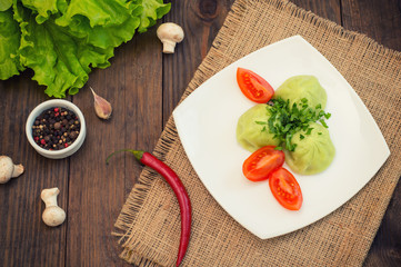 Georgian dumplings Khinkali of spinach dough with meat and tomato spicy sauce satsebeli. Wooden background. Top view. Close-up