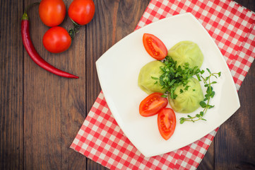 Georgian dumplings Khinkali of spinach dough with meat and tomato spicy sauce satsebeli. Wooden background. Top view. Close-up