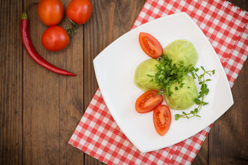 Georgian dumplings Khinkali of spinach dough with meat and tomato spicy sauce satsebeli. Wooden background. Top view. Close-up