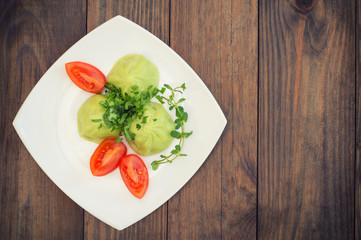 Georgian dumplings Khinkali of spinach dough with meat and tomato spicy sauce satsebeli. Wooden background. Top view. Close-up