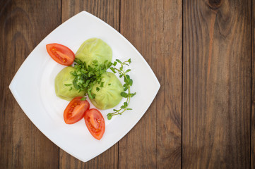 Georgian dumplings Khinkali of spinach dough with meat and tomato spicy sauce satsebeli. Wooden background. Top view. Close-up