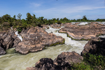 Rough and abundant river white flowing at rock side