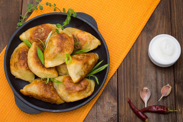 Fried dumplings in the pan. Wooden background. Top view. Close-up