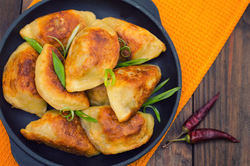 Fried dumplings in the pan. Wooden background. Top view. Close-up