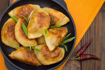 Fried dumplings in the pan. Wooden background. Top view. Close-up