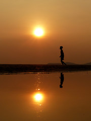 Fototapeta na wymiar Silhouette boy walking on the beach at sunset