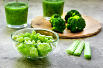 Green vegetable smoothie in glass at gray background