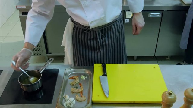 Professional chef's hands putting chopped mushrooms together with shrimps and stirring sauce