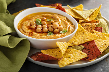 Homemade hummus in white bowl with rainbow corn chips