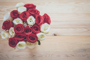 Bouquet of artificial rose flower on wooden plank. Top view