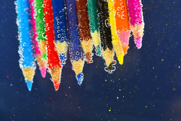 colored pencils in sparkling water