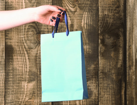 blue shopping bag in female hand on wooden background