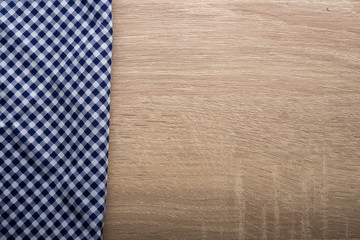 Checkered blue napkin on wooden background.
