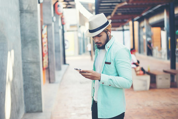 Hipster man listening music with his smartphone on the street.