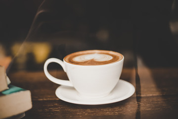 Vintage tone of hot coffee latte art in black cup on table.
