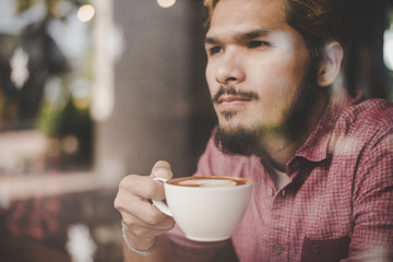 Young man looking away while sitting at the bar in cafe.