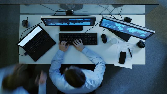 Top View of IT Specialist Working at His Desk, He Monitors International Data Servers, He's Has Discussion with His Manager. Shot as a Time-Lapse.Shot on RED EPIC-W 8K Helium Cinema Camera.
