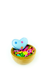 Blue heart and colorful letters in wooden bowl