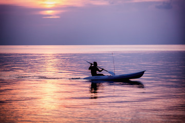 Naklejka premium Silhouette of a man on a sea kayak on a colorful sunset
