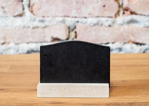 Blank blackboard on wood table top at blur brick background in r