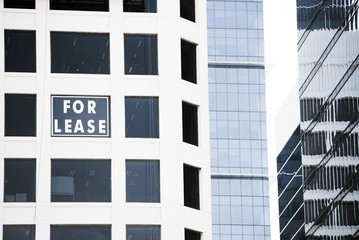 Close up Abstract Conceptual image of Real Estate For Lease sign in window of business building, advertising vacant office and work space to rent, filtered and copy space.