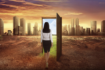 Asian business woman walking to the open wooden door with green environment