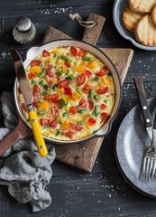 Vegetable frittata in a cast iron skillet on wooden background. Delicious brunch, top view