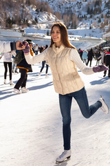 Fototapeta na wymiar Pretty woman ice skating winter outdoors, smiling facial. mountains in the background