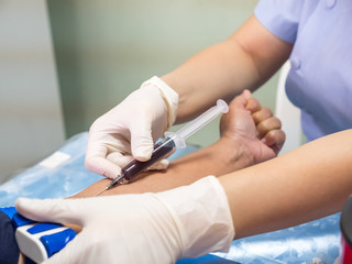nurse with syringe is taking blood for test at the laboratory