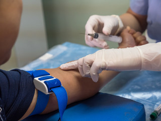 nurse with syringe is taking blood for test at the laboratory