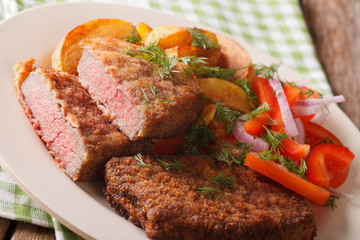 Breaded round steak with potato and vegetables close-up. horizontal