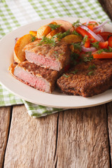 rump steak in breadcrumbs and fresh vegetables, baked potatoes close up. vertical