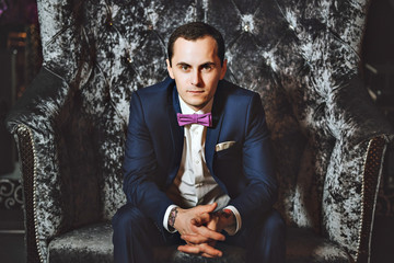 The man on the chair. In a blue suit, purple tie.