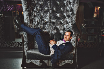 The man on the chair. In a blue suit, purple tie.
