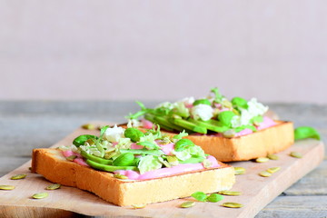 Sandwiches with white bread, avocado, lettuce mix, pumpkin seeds, basil and sauce. Useful sandwiches on a wooden board. Background with copy space for text