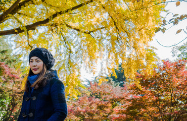 Young Asian girl with background of yellow and red leaves in the park during autumn season