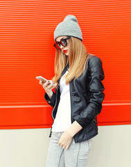 Fototapeta premium Fashion stylish young woman using smartphone walking in city ove