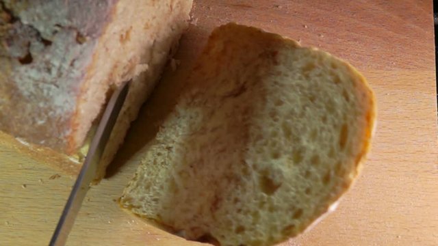 View from above on slow motion of knife cutting off a loaf grain bread