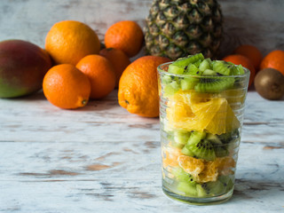 Colorful fruit salad in a jar on rustic wooden table. Fruits on the background