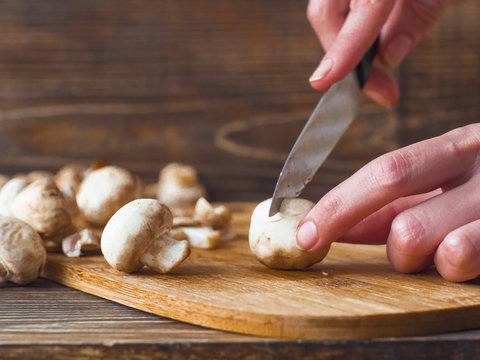 Woman hands slices mushrooms in kitchen. Female making mushroom sauce