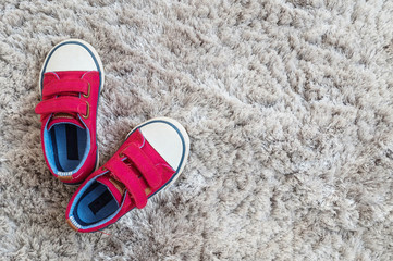 Closeup red fabric sneakers of kid on gray carpet textured background in top view with copy space