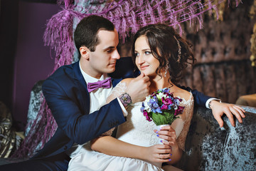 Wedding day. The bride and groom in a luxurious interior in lavender color. Wedding emotions. Beautiful bride and elegant groom at the ceremony.